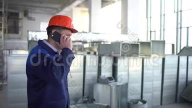 年轻的白种人工程师在正在建造的大楼里打电话。 戴橙色安全帽的档案馆